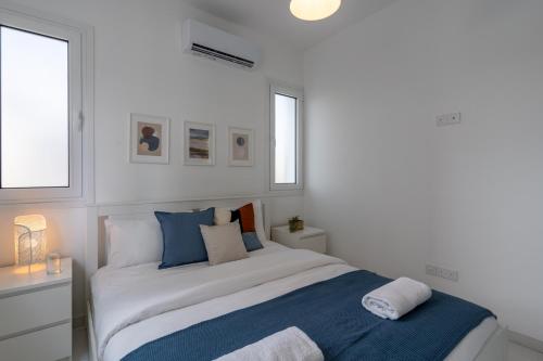um quarto branco com uma cama e 2 janelas em Artemis 1-Bedroom Apartment in Larnaca em Larnaka