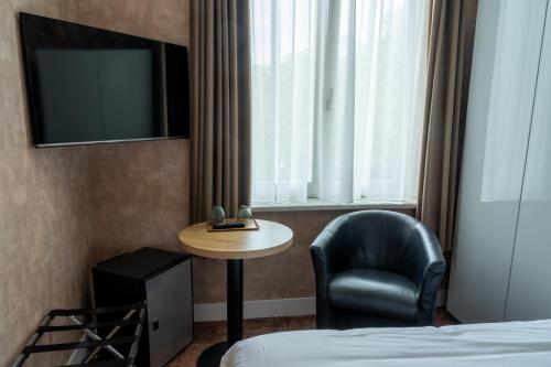 a hotel room with a table and a chair and a bed at Hotel Canteklaar in De Haan