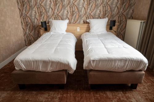 two beds sitting next to each other in a room at Hotel Canteklaar in De Haan