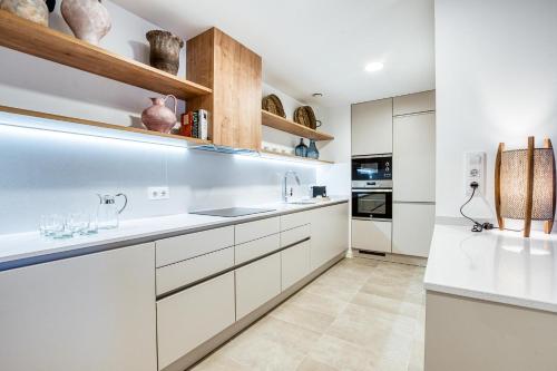 a kitchen with white cabinets and white appliances at CAMBRILS Chic! Apartments by ALEGRIA in Cambrils