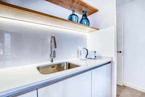 een keuken met een wastafel en blauwe flessen op een plank bij CAMBRILS Chic! Apartments by ALEGRIA in Cambrils