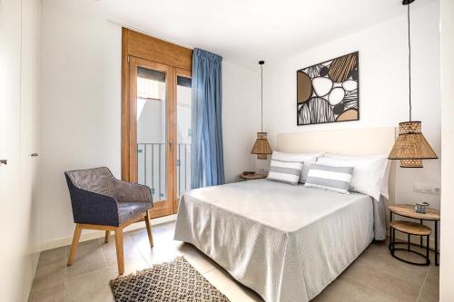 um quarto com uma cama, uma cadeira e uma janela em CAMBRILS Chic! Apartments by ALEGRIA em Cambrils