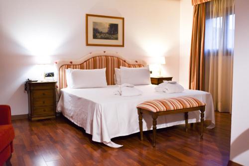 a bedroom with a bed with white sheets and a chair at ALEGRIA Bodega Real in El Puerto de Santa María