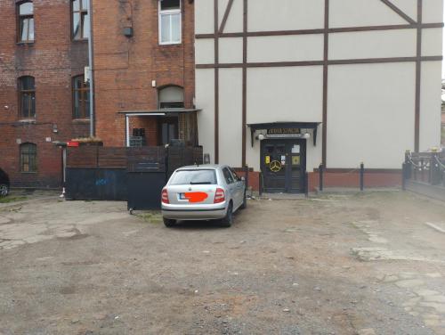 un coche aparcado en un aparcamiento frente a un edificio en Pokoje gościnne w centrum en Wałbrzych