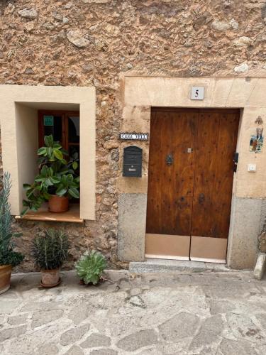 un bâtiment en pierre avec une porte en bois et deux plantes en pot dans l'établissement Casa Vell de Valldemossa, à Valldemossa