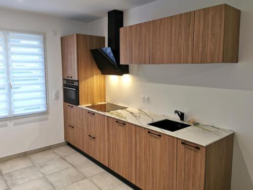 an empty kitchen with wooden cabinets and a window at La Petite Marine a 150m de la plage in Brétignolles-sur-Mer