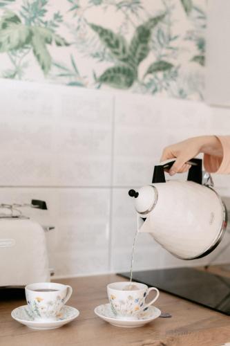 a woman pouring coffee into two cups on a table at Vacanza Park in Łeba
