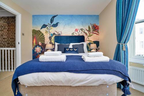 ein Schlafzimmer mit einem blauen Bett und einem Gemälde an der Wand in der Unterkunft Finest Retreats - Brighton House in Brighton & Hove