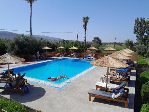 a swimming pool with people laying in chairs and umbrellas at Aegean Pearl in Tigaki