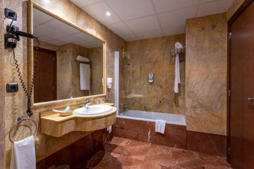 a bathroom with a sink and a tub and a mirror at Hotel Aroi Bierzo Plaza in Ponferrada