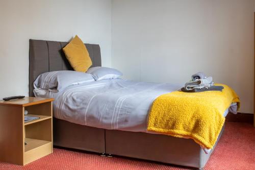 a bedroom with a bed with a yellow blanket at The George Hotel in Chatteris
