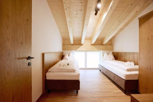 Alpenstolz Damüls Haus 1 - Stilvoll urlauben in den Bergen في دامولس: سريرين في غرفة بسقوف خشبية