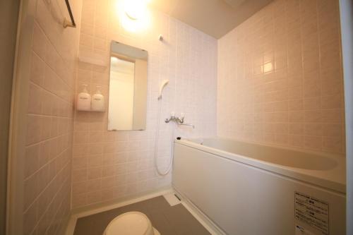 een badkamer met een bad, een toilet en een wastafel bij Kisyaba Hotel in Kagoshima