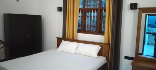 a small bedroom with a bed and a mirror at Villa 142 in Weligama
