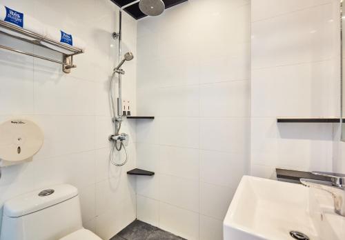 a white bathroom with a toilet and a sink at ibis budget Singapore Pearl in Singapore