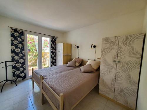 ein Schlafzimmer mit einem großen Bett und einem Fenster in der Unterkunft Le Salvador - maisonnette pour 4 in Sigean
