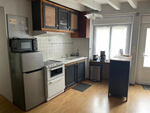 Il comprend une cuisine équipée d'un réfrigérateur et d'une cuisinière. four supérieur dans l'établissement Maison de bourg sans jardin, à Pleucadeuc