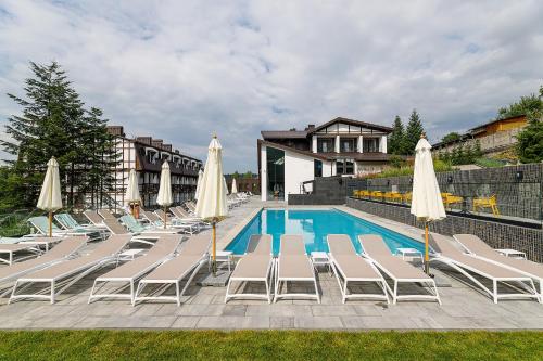 a swimming pool with lounge chairs and umbrellas at Crona SPA Karpaty in Skhidnitsa