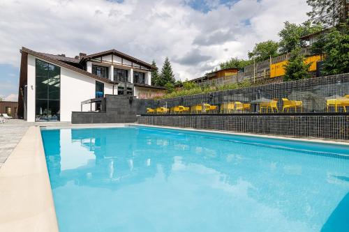 a large blue swimming pool in front of a house at Crona SPA Karpaty in Skhidnitsa
