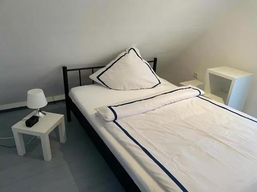 Cama blanca con almohada y mesa auxiliar en room4rent 