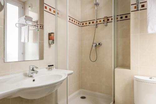 y baño con lavabo y ducha. en Hotel Elysée Etoile, en París