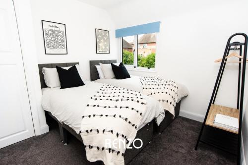 ノッティンガムにあるCosy 3-bed Home in Nottingham by Renzo, Driveway for 2 Cars, Perfect for Contractors!のベッドルーム1室(大型ベッド1台、白黒の枕付)