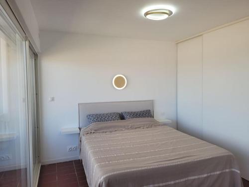 1 cama en un dormitorio con una pared blanca en Le Front de mer - vue imprenable, en Port-la-Nouvelle