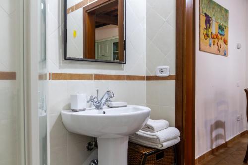 een badkamer met een wastafel, een spiegel en handdoeken bij Farfalla in Montiano