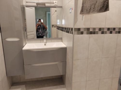 uma mulher tirando uma foto de uma casa de banho com um lavatório em chez martine em Saint-Mitre-les-Remparts