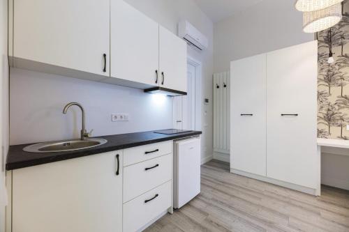 a white kitchen with a sink and white cabinets at Partner Guest House Baseina in Kyiv