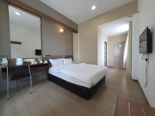 a bedroom with a bed and a desk and a television at Hotel Golden View Nilai in Nilai