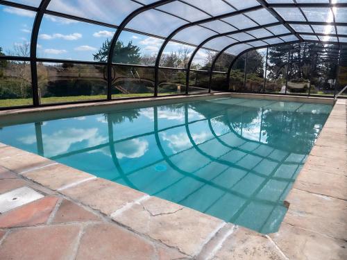 une grande piscine avec une arche au-dessus de celle-ci dans l'établissement Domaine aux Lions - Piscine Tennis 20 min Deauville, à Fauguernon