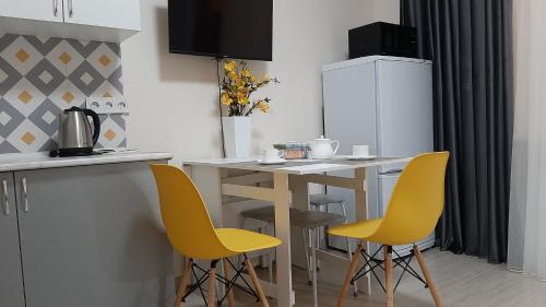 a kitchen with a table and two yellow chairs at Уютная евродвушка в центре, ЖК Атлант in Almaty