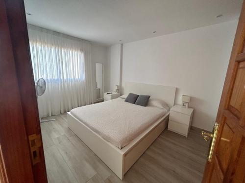 a white bedroom with a bed and two night stands at Apartamento en Los Cristianos in Los Cristianos