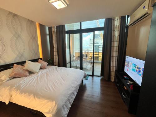 a bedroom with a bed and a flat screen tv at Appleone Ayala Condo with Balcony in Cebu City