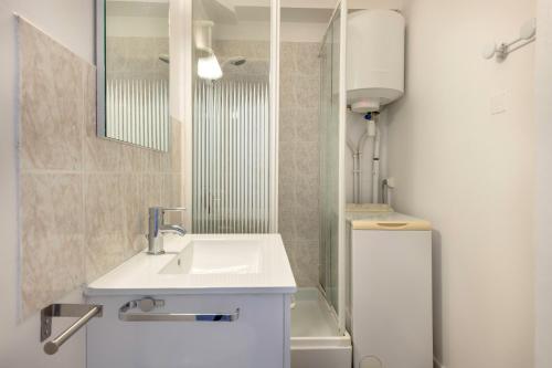 a white bathroom with a sink and a mirror at St Brévin - Studio - 4 Pers - Vue Mer in LʼErmitage