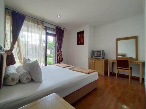 een slaapkamer met een bed met een spiegel en een raam bij Villa Bukit Danau Lot 14 in Cinengangirang