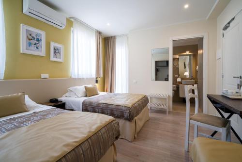 a hotel room with two beds and a desk at Hotel Rivage Taormina in Taormina
