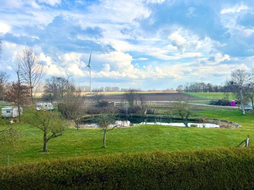 ein Feld mit einem Teich und einer Windturbine in der Unterkunft Seemöwe Wohnung in Rostock