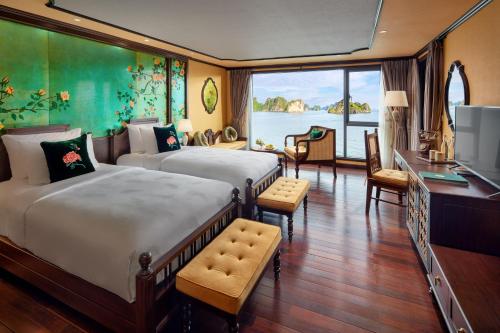 Indochine Premium Halong Bay Powered by Aston في ها لونغ: غرفة نوم بسريرين ومكتب وتلفزيون