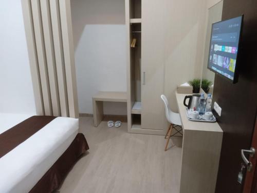 a hotel room with a bed and a desk with a television at Dawala Hotel in Sudiang