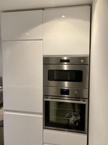 un four en acier inoxydable dans une cuisine avec des armoires blanches dans l'établissement Plage du Couchant, à La Grande Motte