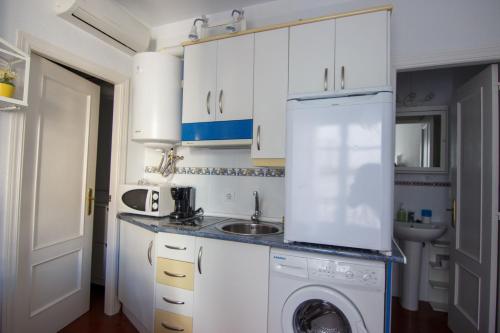 een witte keuken met een wastafel en een wasmachine bij RentalSevilla Enjoy Seville in Sevilla