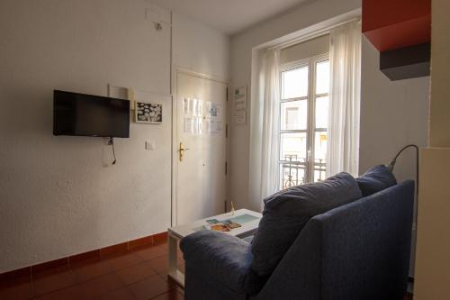 een woonkamer met een blauwe bank en een tv bij RentalSevilla Enjoy Seville in Sevilla