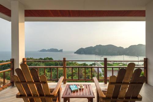 a balcony with chairs and a table and a view of the water at Phi Phi Mountain Beach Resort SHA Certified in Phi Phi Don