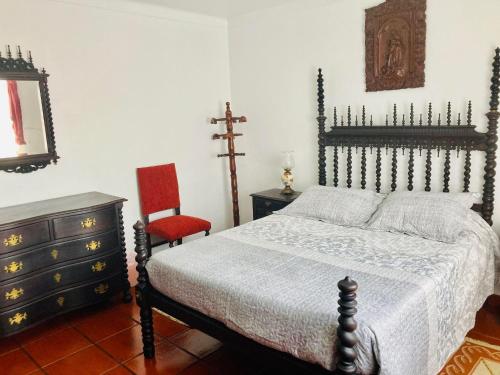 a bedroom with a bed and a chair and a dresser at Alfazema in São Sebastião