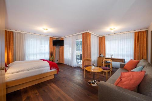 ein Hotelzimmer mit einem Bett und einem Sofa in der Unterkunft Hotel Alex Business & SPA in Naters