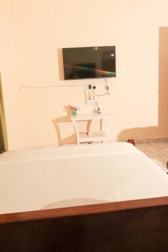 ein Krankenhauszimmer mit einem Bett und einem TV an der Wand in der Unterkunft AMELIA BNBS in Mtwapa