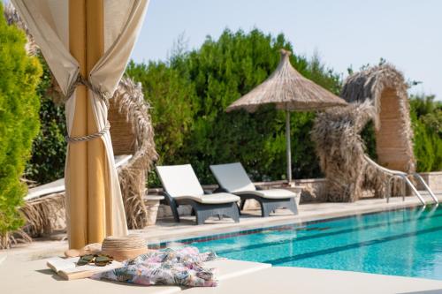 a swimming pool with chairs and umbrellas next to a resort at Elefteria Apts & Suites in Kolimbia