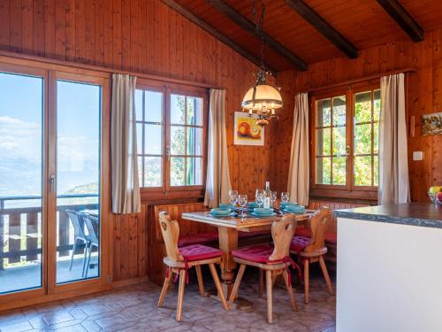 a dining room with a table and chairs and windows at Chalet Mustela by Interhome in Nendaz